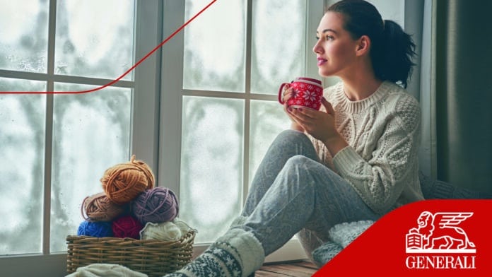 Vakker ung kvinne sitter ved vinduet og ser på frossent glass. Jente nyter varm drikke.